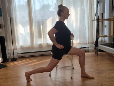 A woman practicing a seated lunge on a chair