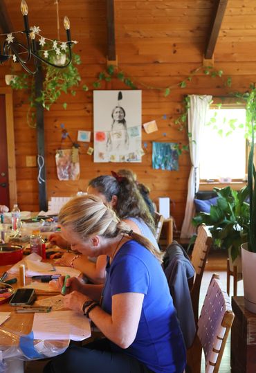 A group of women gathered around a table doing art