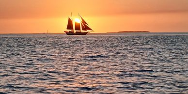 Sailboat silhouetted against a vibrant sunset over calm waters.
