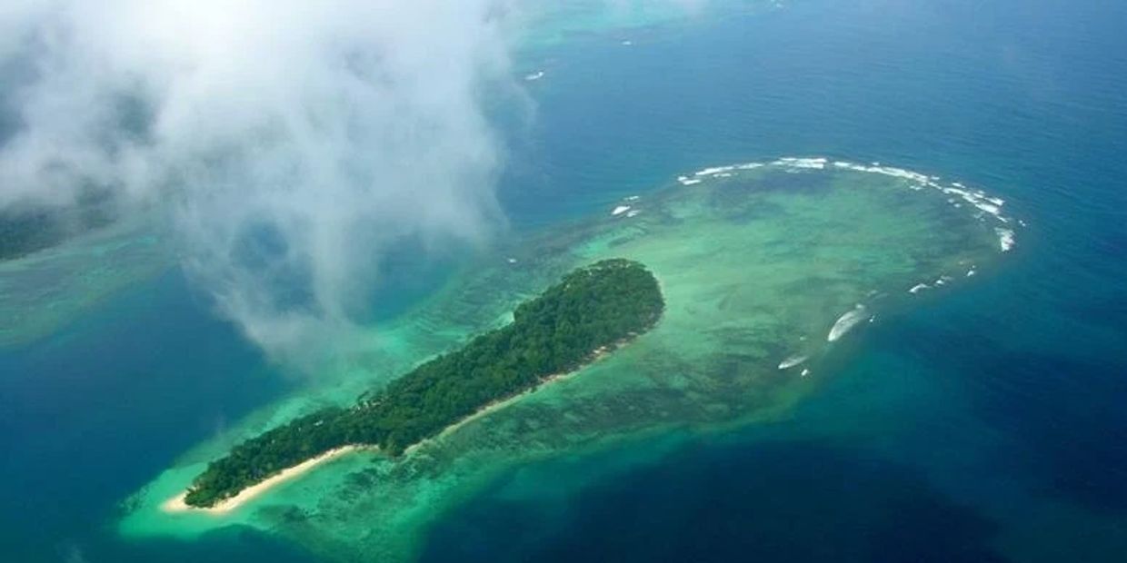 Aerial view of a lush island surrounded by turquoise waters and white sandy beaches.