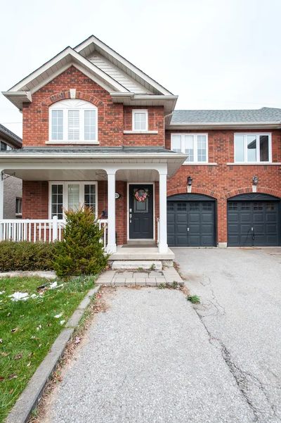 a two-story red brick house with black double garage doors and a white front porch.