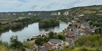 Scenic riverside village with boats and cliffs.