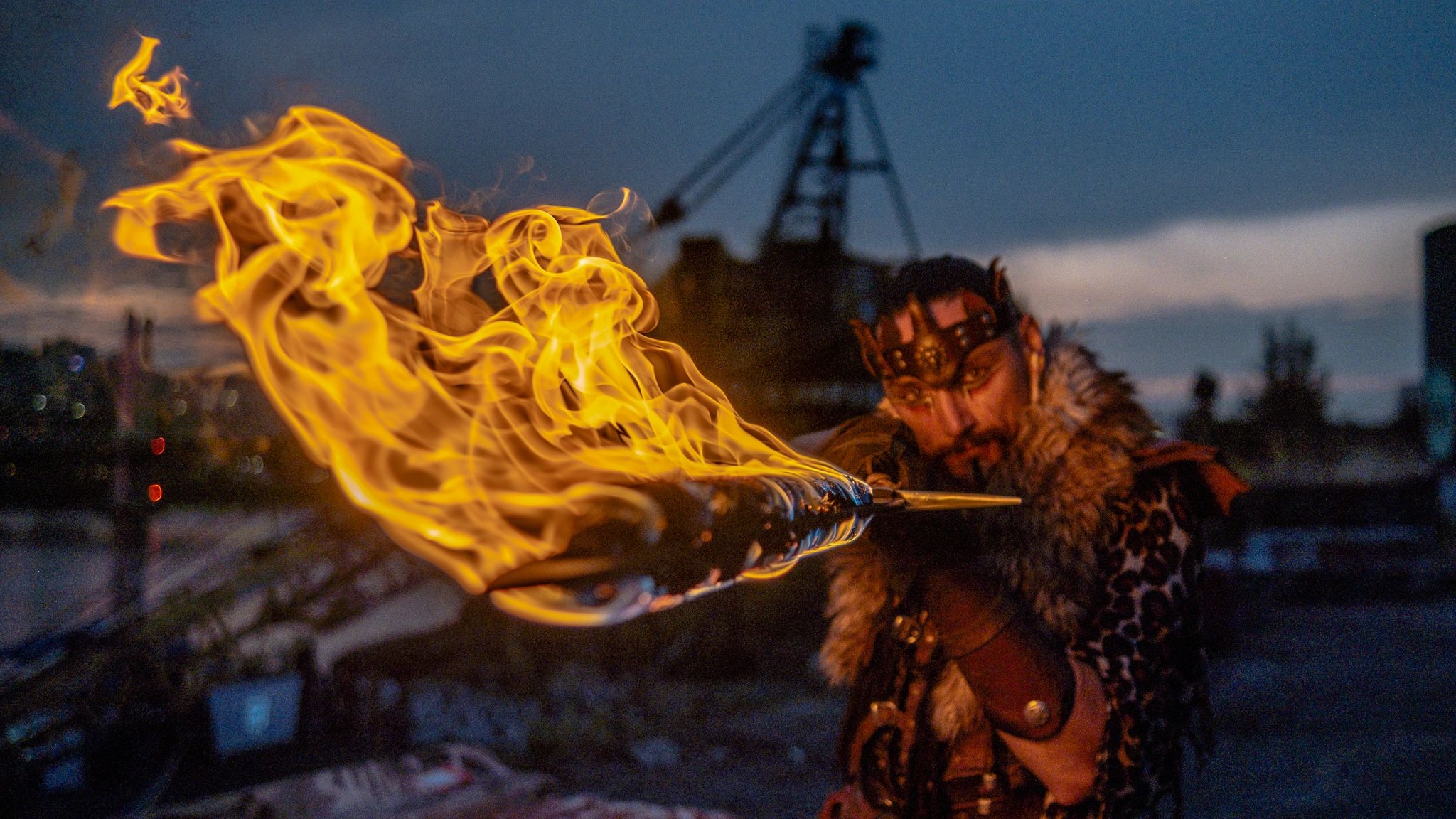 Cosplay Viking warrior posing with a flaming sword in a dramatic urban setting