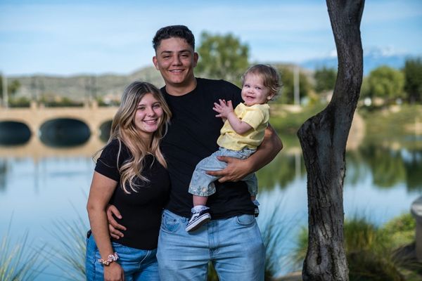 A young family in front of a lake with a smiling baby.  Family photography, portrait photography.