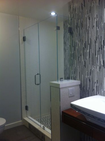 Modern bathroom with glass shower and patterned tiles.