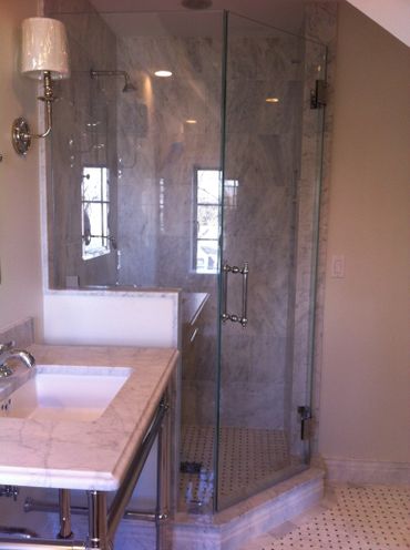 Elegant bathroom with marble surfaces and glass shower enclosure.