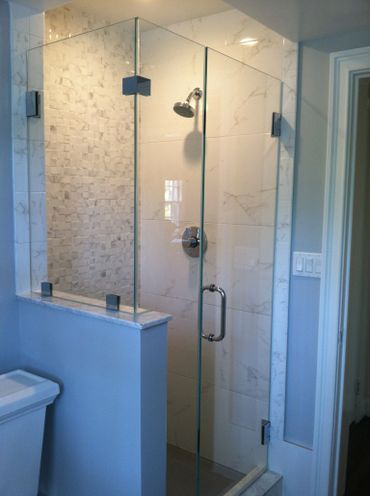 Modern glass shower enclosure with marble tiles and chrome fixtures.