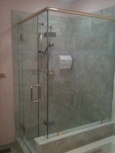 Modern glass shower enclosure with tiled walls and built-in soap dispensers.