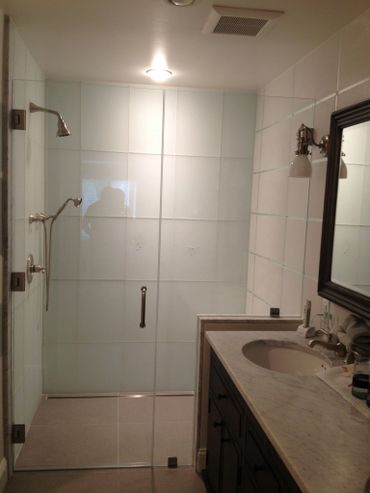 Modern bathroom with glass shower enclosure and marble countertop vanity.