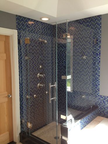 Modern bathroom with glass shower and blue mosaic tiles.