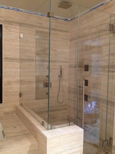 Modern bathroom with beige stone walls and glass shower enclosure.