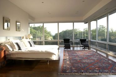 Spacious bedroom with large windows and a scenic forest view.