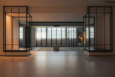 Modern empty room with large windows and geometric metal frames.