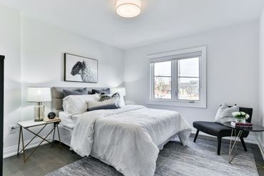Bright modern bedroom with white bedding and artistic sheep painting.