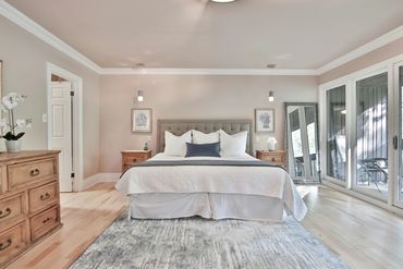 Bright and cozy bedroom with large windows and wooden furniture.