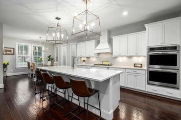 Modern kitchen with white cabinetry, island, and brown leather bar stools.