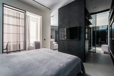 Modern bedroom with black accent wall and mounted TV.