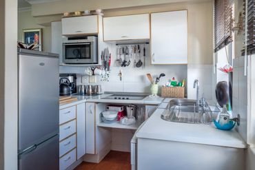 Compact kitchen with white cabinets, stainless appliances, and organized utensils.