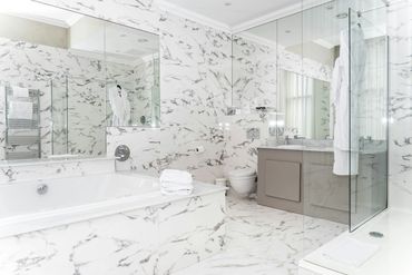 Luxurious white marble bathroom with modern fixtures and glass shower.