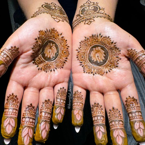 Intricate henna designs on palms with floral and leafy patterns.