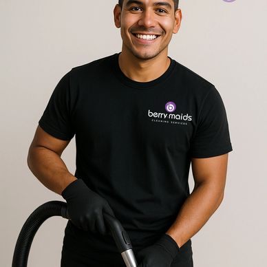 Smiling cleaning professional in black uniform holding a vacuum hose.