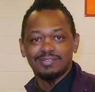 Portrait of a man smiling in an indoor setting.