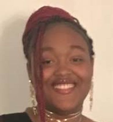 Smiling woman with braided hair and elegant jewelry.