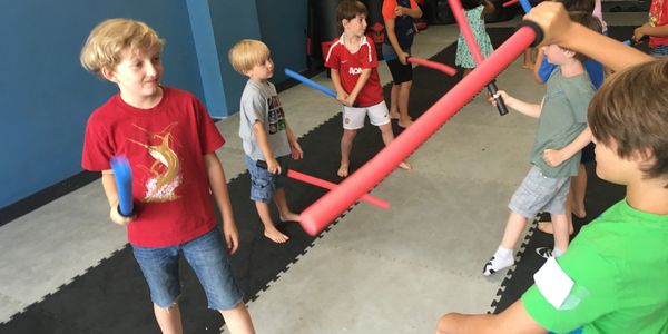 Children play with foam swords in an indoor play area.