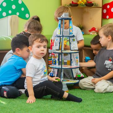 Children playing a stacking game at Fun Two Three Russian Daycare