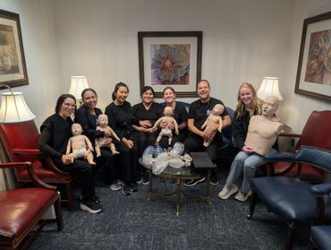 Group of people holding CPR mannequins in a training room.
