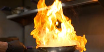 Large flame rising from a pan while cooking.