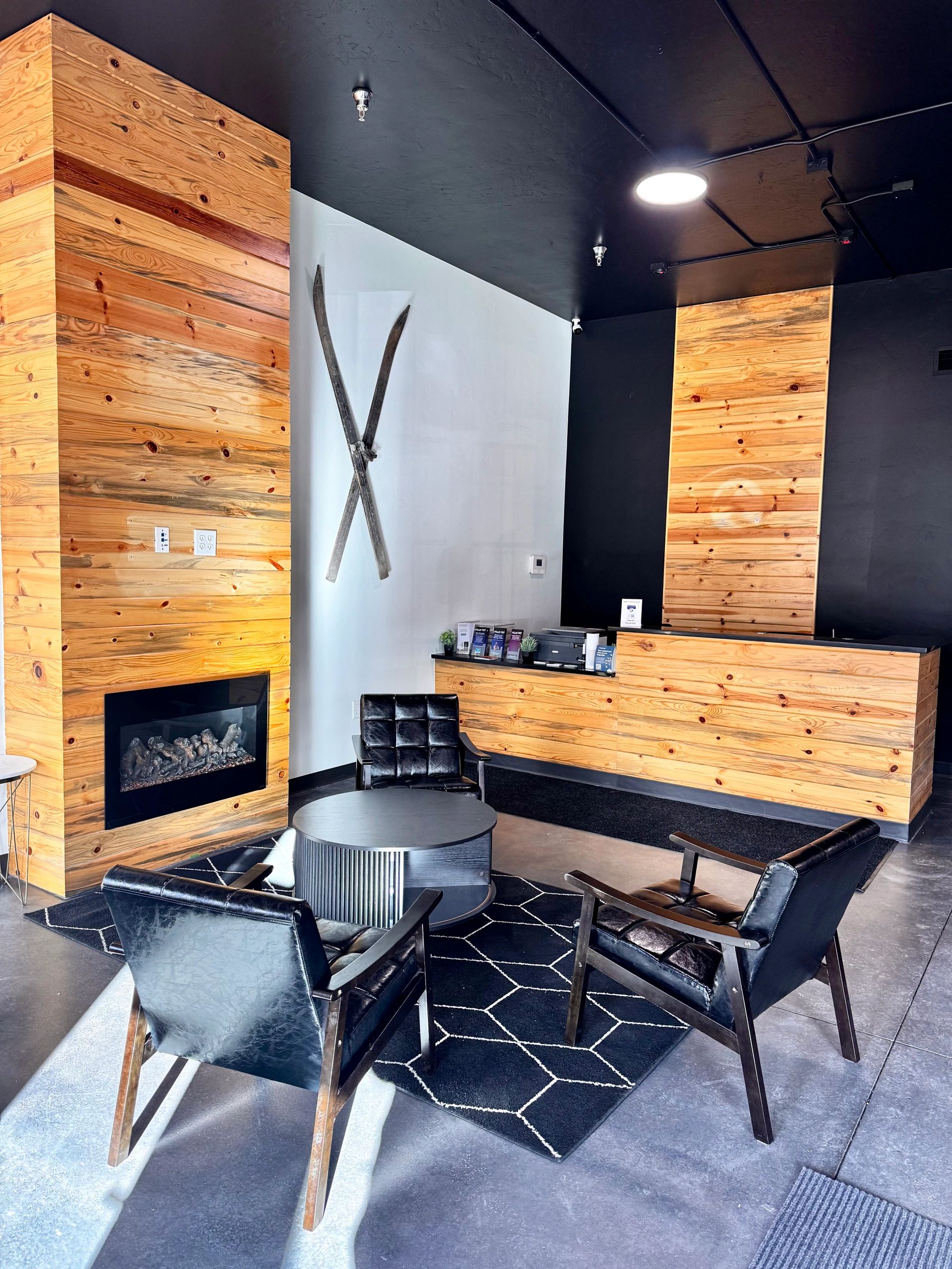 Modern lobby with wooden accents, black leather chairs, and a fireplace.