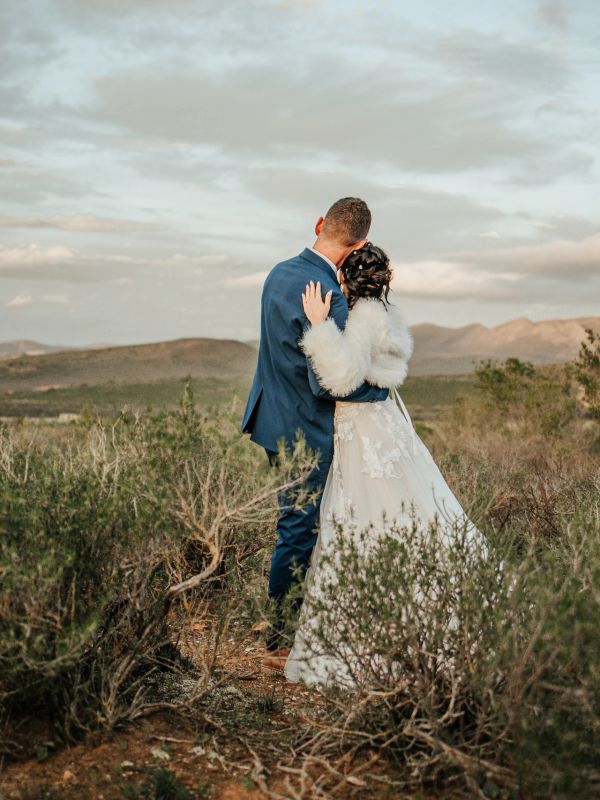 Couple embracing in a scenic outdoor setting on their wedding day.