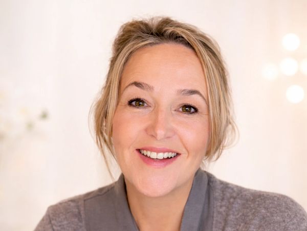 Smiling middle-aged woman with light makeup and casual attire.