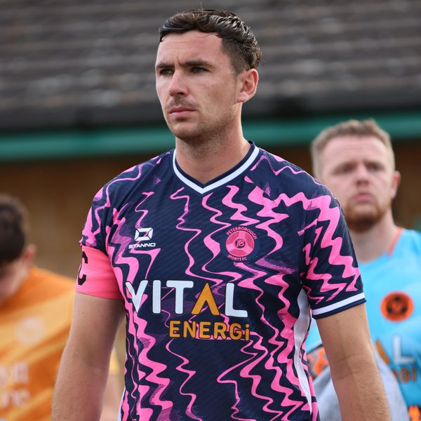 Soccer player in a pink and navy zigzag jersey planning.