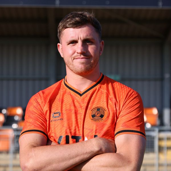 Man in an orange sports jersey posing with arms crossed.
