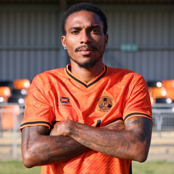 Athlete in an orange sports jersey with crossed arms.