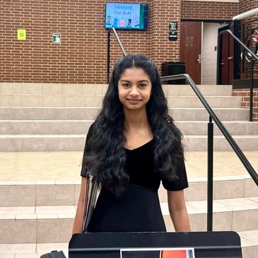 Young woman with long curly hair standing outside on steps.