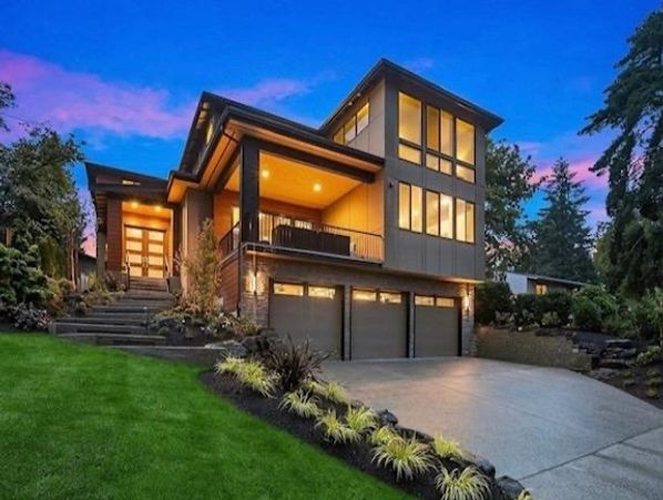 Stylish home captured at dusk with illuminated windows, a spacious garage, and landscaped garden, showcasing modern architecture.