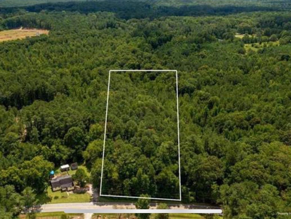 Aerial view of a forested property outlined for development on Clark Road, surrounded by mature trees with nearby homes