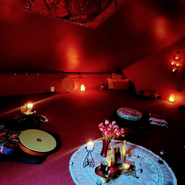 Cozy dimly lit room with candles and cushions.