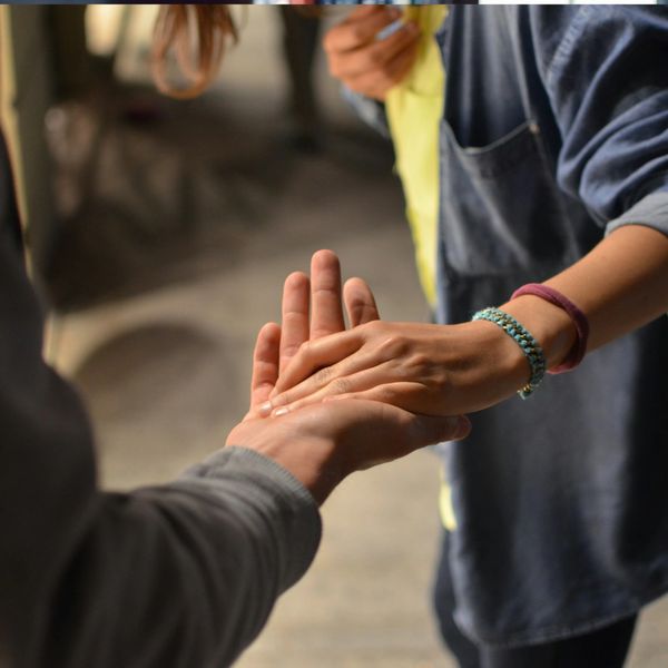 Image of someone reaching out and another person looking back and holding their hand.