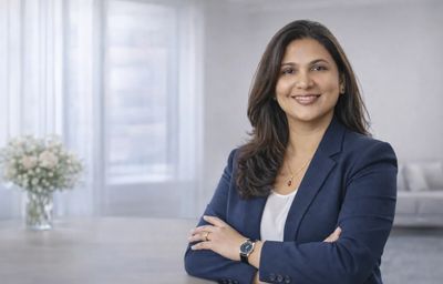Professional woman in a navy blazer smiling confidently indoors.