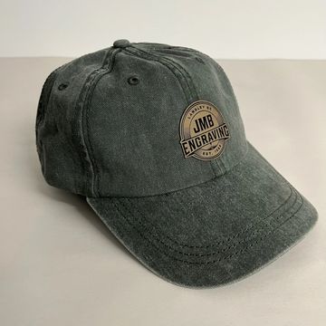 Forest Green hat with a sandstone/black patch engraved with the JMB Logo. 