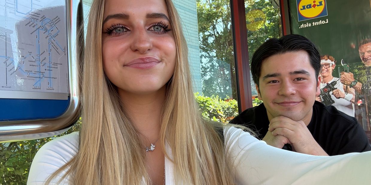 Zwei Personen machen ein Selfie an einer Bushaltestelle.