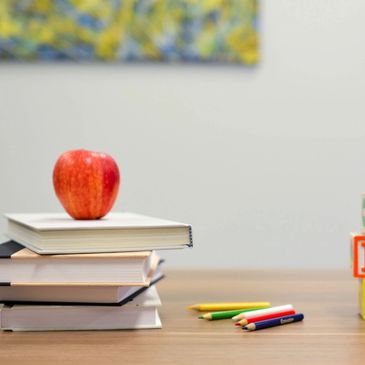 Roter Apfel auf einem Stapel Bücher auf einem Holztisch.