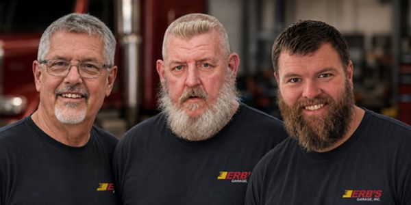 Three men smiling in a garage setting.