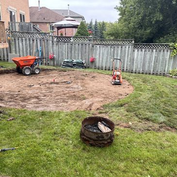 Backyard lawn renovation with tools and bare soil patch.