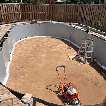 Empty pool under construction with tools and dirt floor.