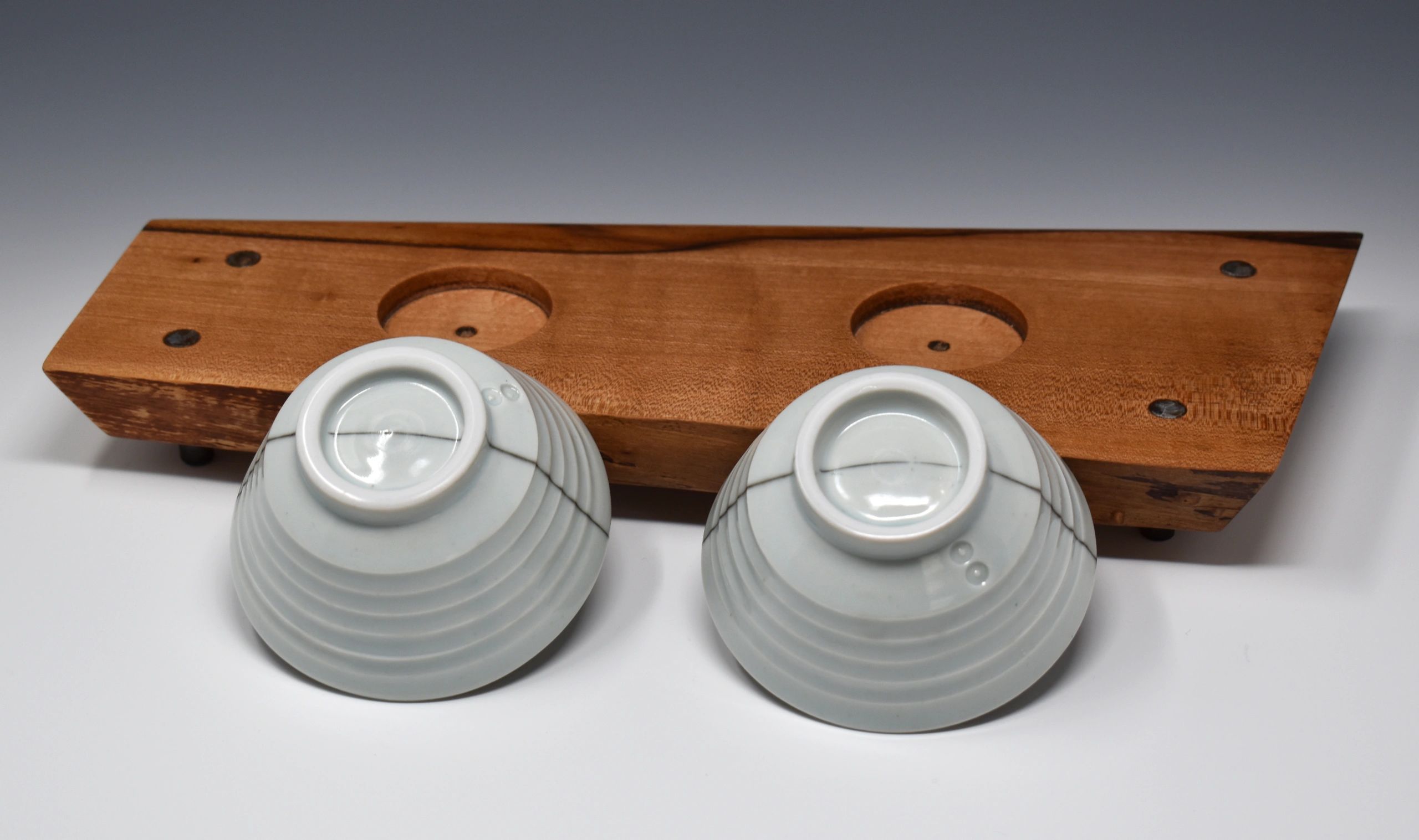 Two porcelain copitas upside down leaning against a wood tray.